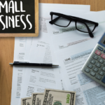 Papers and Pen and Calculator and Coffee and Small Business Sign | Safeguard | 3 Small Business Risks to Know: Inflation, Wage Changes, & Threatened Business Growth in 2022